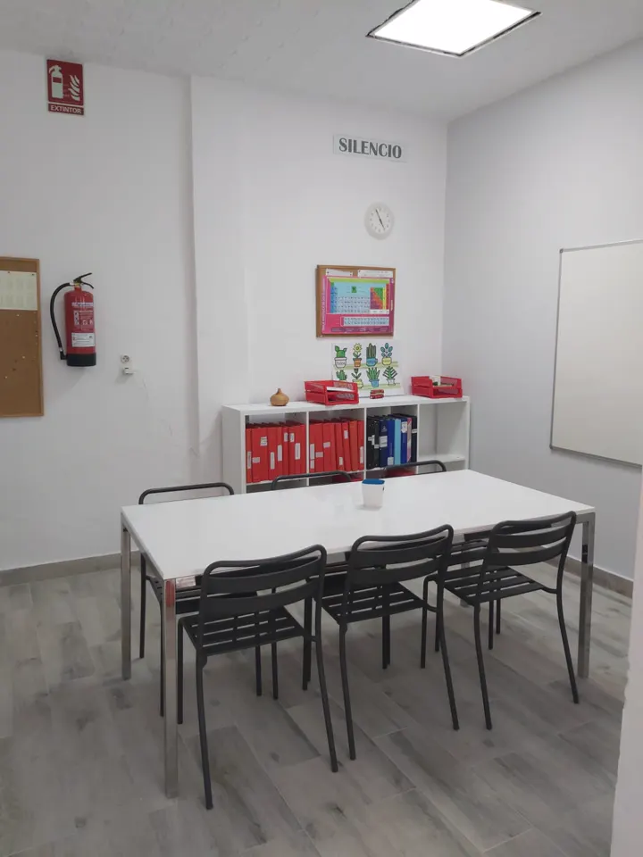 Aula con mesa para ocho, pizarra y cartel de silencio